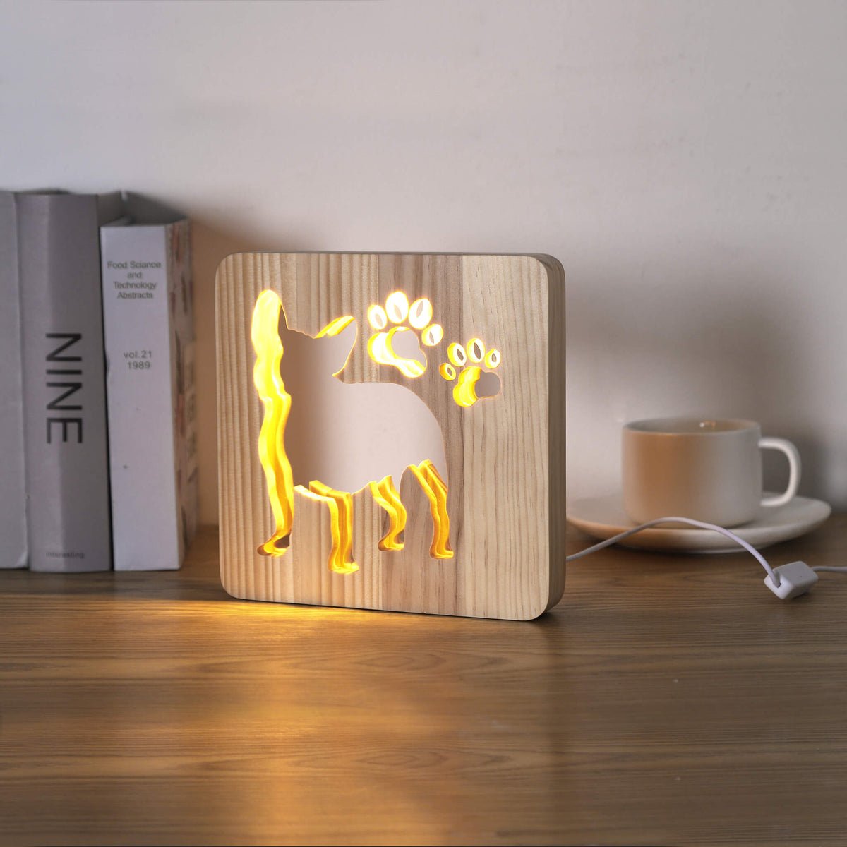 French Bulldog LED night light switched on, on a desk beside books and a mug