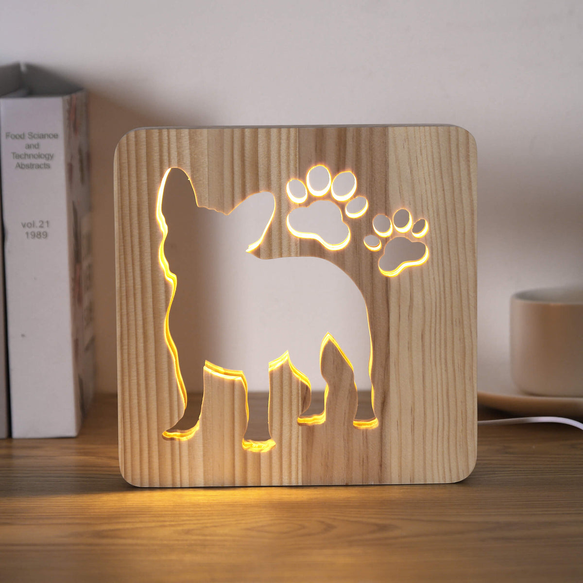 Lit French Bulldog USB night light on a desk next to books