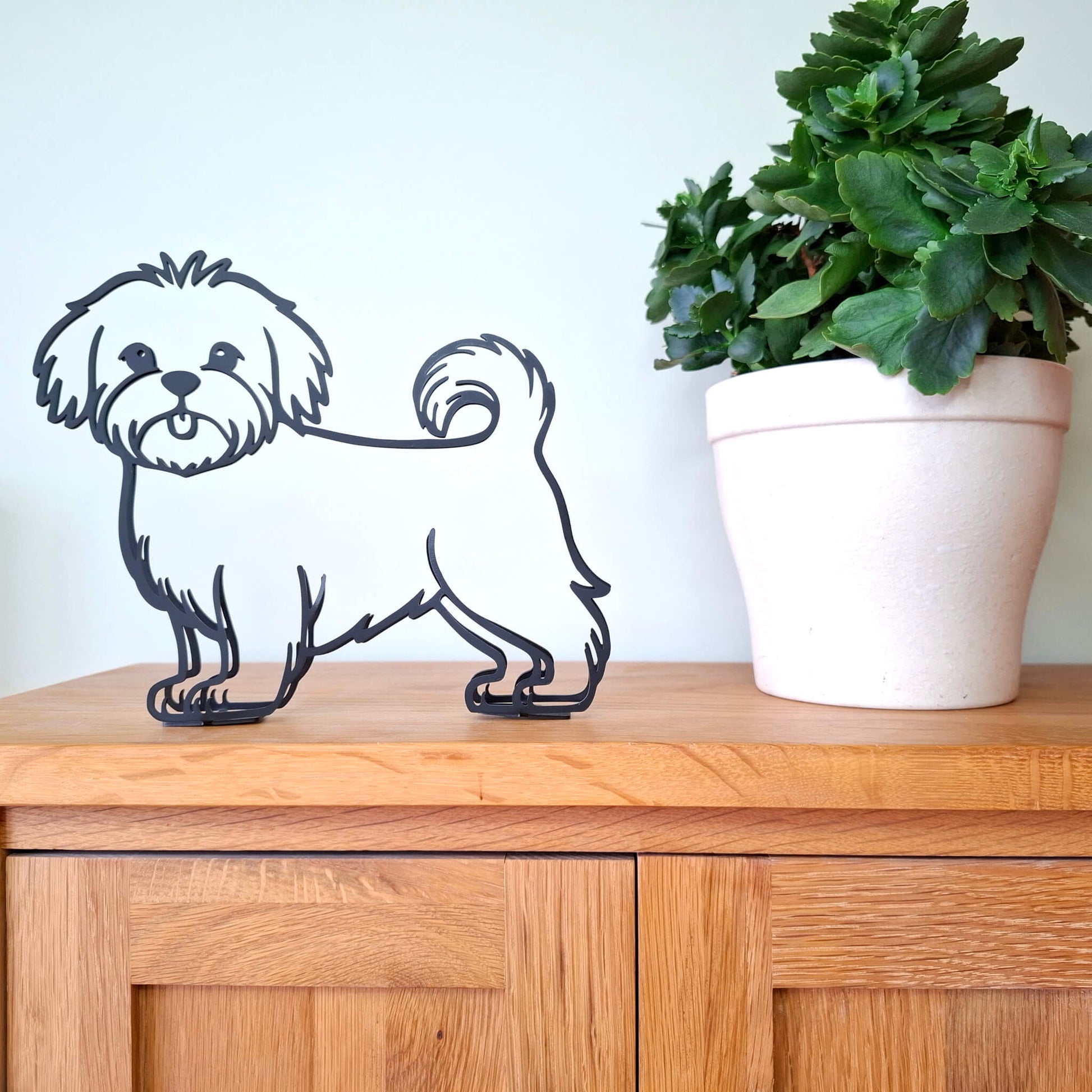 black metal maltese dog figurine displayed on wooden shelf