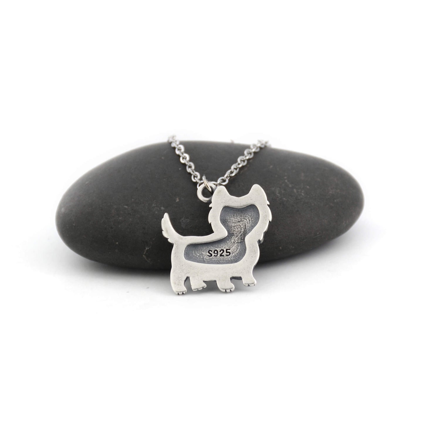 back view of silver westie charm displayed against a pebble