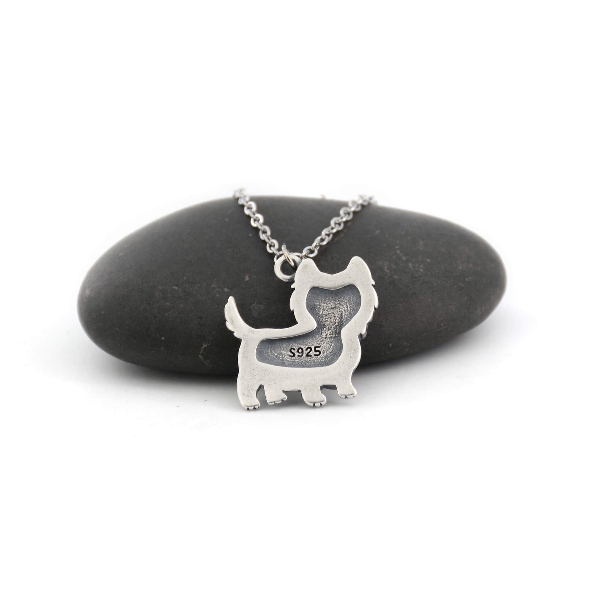 back view of silver westie charm displayed against a pebble