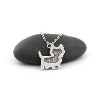back view of silver westie charm displayed against a pebble