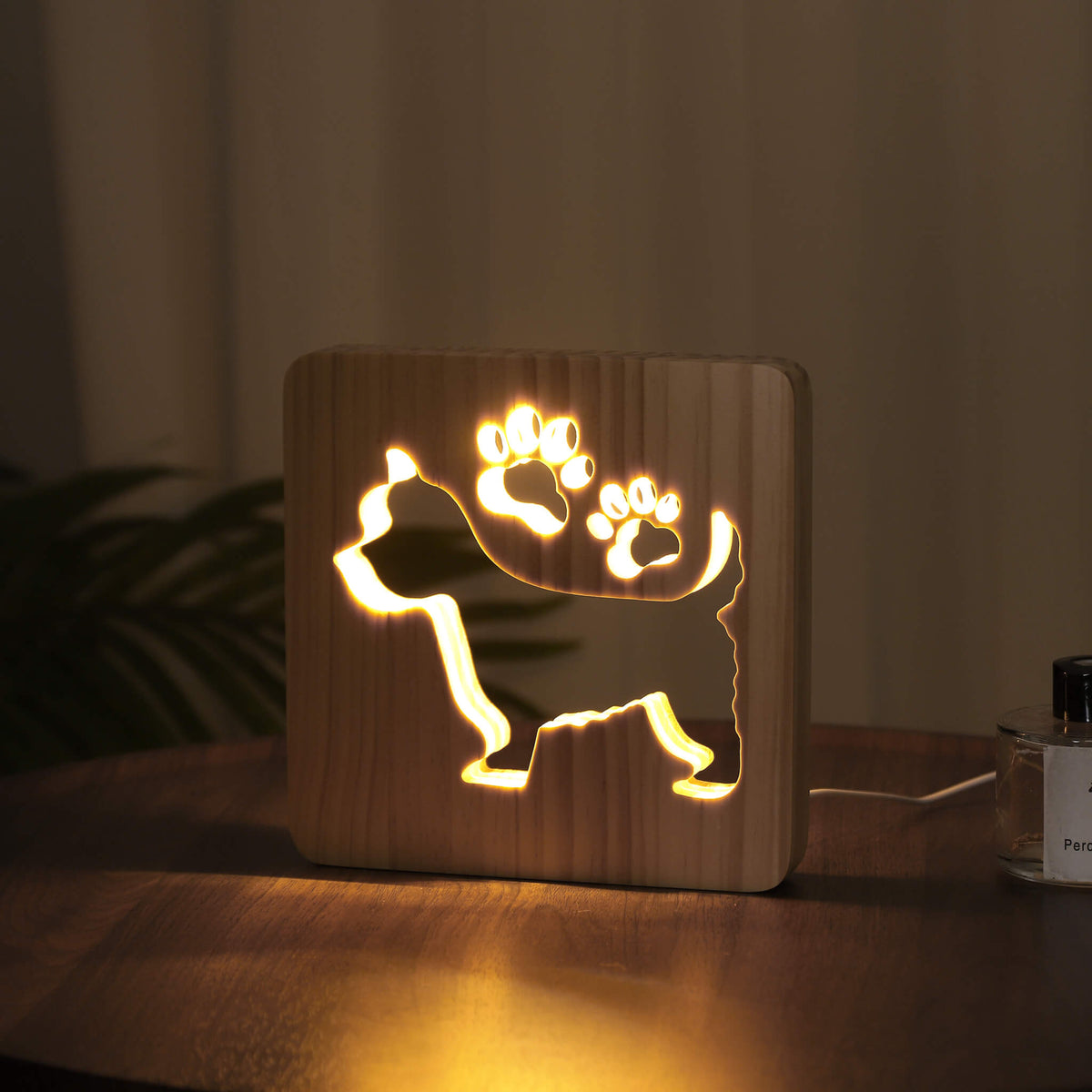 Side angle of the glowing Westie wooden night light in a dark room